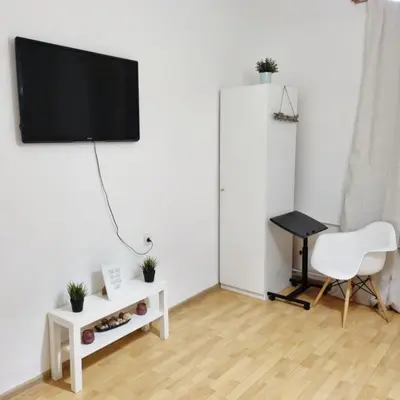 a living room with a tv and a chair and a desk at Apartment for four next to blvd Vitosha in Sofia