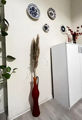 a red vase with a plant in it next to a refrigerator at Great location in the Center in Sofia