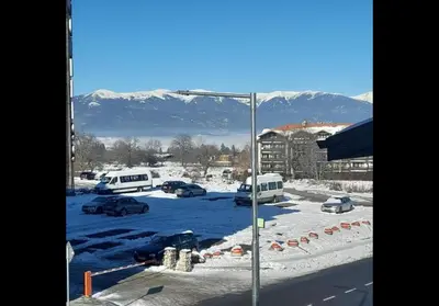 a parking lot with cars parked in the snow at GONDOLA APARTMENTS BANSKO - SUVOROV VIP Complex in Bansko