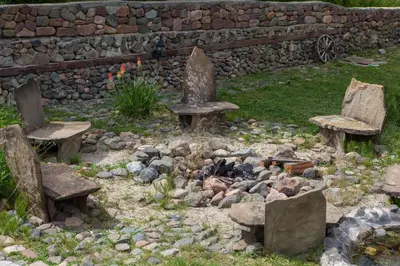 a garden with two chairs and a stone wall at Самостоятелна къща за гости с изглед към планината Вила Марк in Kraevo