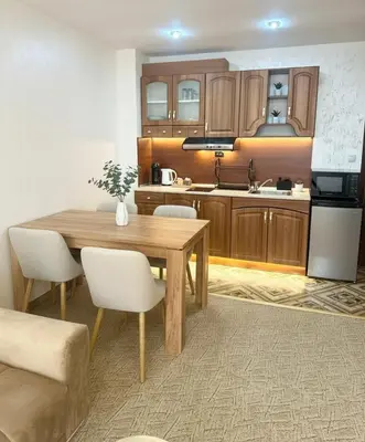 a kitchen with a wooden table and white chairs at Raya Apart Pamporovo in Pamporovo