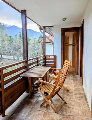 a wooden table and chairs on a balcony with a view at Bansko holiday apartments - Mountain View Resort in Bansko