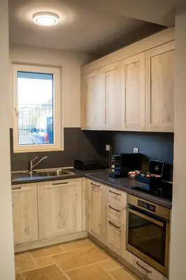 a kitchen with wooden cabinets and a sink and a window at Къщи за гости ПАВЛЕВСКИ in Banya