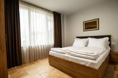 a bedroom with a bed with white sheets and a window at Къщи за гости ПАВЛЕВСКИ in Banya