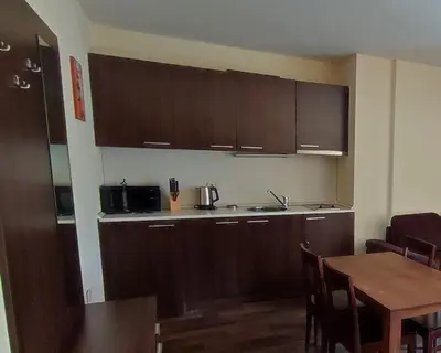 a small kitchen with wooden cabinets and a table at Aspen Apartment A409 3OOm from Gondola in Bansko