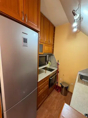 a kitchen with a stainless steel refrigerator and wooden cabinets at Mall Bulgaria Apartment in Sofia
