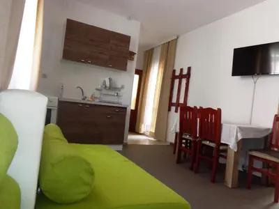 a living room with a green couch and a kitchen at ViBo Guesthouse in Sapareva Banya