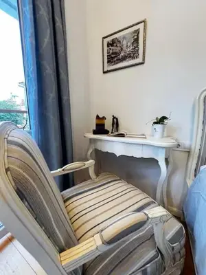 a chair in a room with a table and a window at Christine's Apartment in Sofia