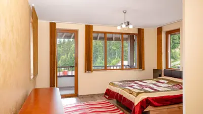 a bedroom with a bed and some windows at Penthouse Astralis - Pamporovo in Pamporovo
