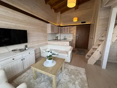 a living room with a couch and a tv and a table at Pirin Golf SP Apartments in Razlog