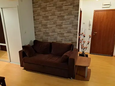 a brown couch in a living room with a brick wall at Уютен апартамент за зимна почивка в Пампорово in Pamporovo