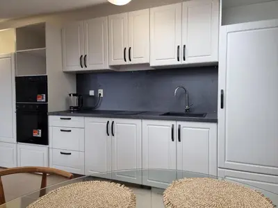 a kitchen with white cabinets and a glass table at Belvedere private apartment 1-bedroom with balcony in Bansko