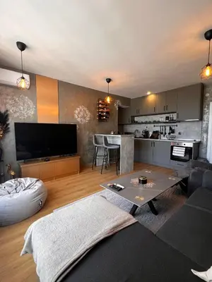 a living room with a large television and a kitchen at CozyHomes in Bansko