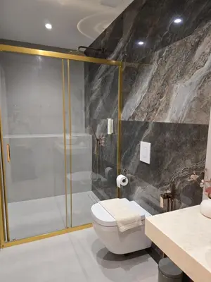 a bathroom with a toilet and a glass shower at Луксозни делукс стаи Мечката in Botevgrad