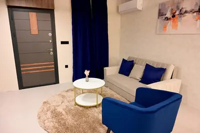 a living room with a couch and a table and blue chairs at Луксозни делукс стаи Мечката in Botevgrad
