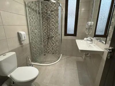 a bathroom with a shower and a toilet and a sink at Семеен хотел БОНЖУР in Panagyurishte