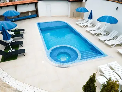 an overhead view of a swimming pool with chairs and umbrellas at Семеен хотел БОНЖУР in Panagyurishte