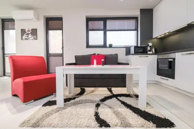 a living room with a white table and a red chair at Heart of Plovdiv Studio Apartment Free Parking in Plovdiv