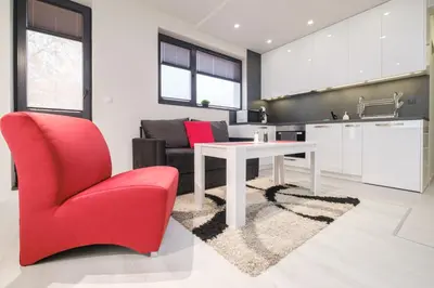 a kitchen and living room with a table and a red chair at Heart of Plovdiv Studio Apartment Free Parking in Plovdiv