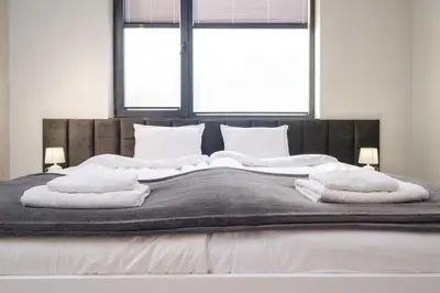 a bed with white towels on it with two windows at Heart of Plovdiv Studio Apartment Free Parking in Plovdiv