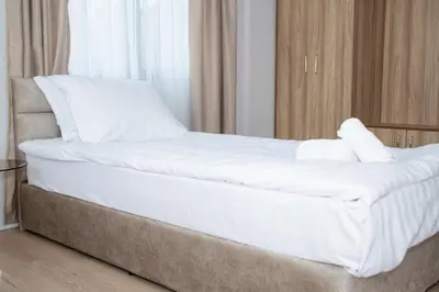 a bed with white sheets and pillows in a room at Орбелус in Bansko