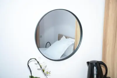 a mirror hanging on a wall with a bed at Орбелус in Bansko