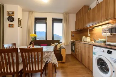 a kitchen and living room with a table and a laundry machine at Niki's cosy place in Bansko