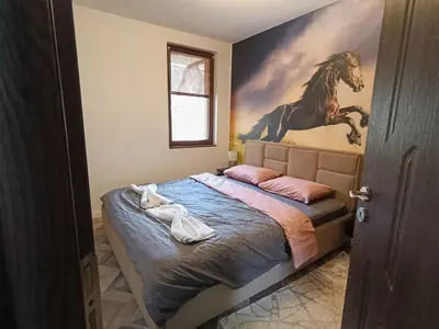 a bedroom with a bed with a horse painting on the wall at Ski cosy apartment 5 in Bansko