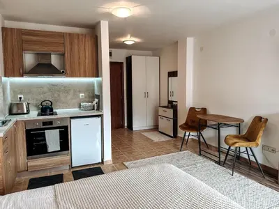 a kitchen with a stove and a table in a room at Pirin Apartament in Bansko