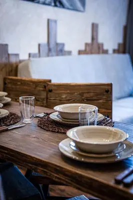a wooden table with plates and glasses on it at Host2U Authentic Bansko Apartment - Free Parking in Bansko