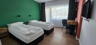 two beds in a room with a green wall at Къща за гости ЕСТЕТ ESTET Guest house in Oreshak