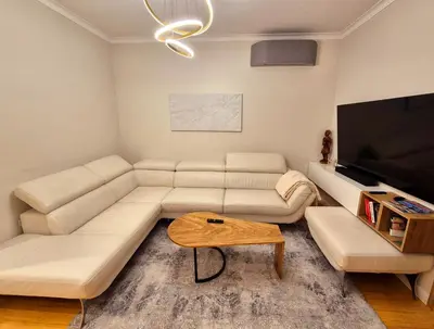 a living room with a white couch and a flat screen tv at The VERTEX in Sofia