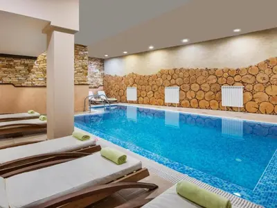 a pool in a hotel room with lounge chairs at Snowflake- Luxury stay with a Bottle of Wine,free Parking and SPA in Royal Park in Bansko