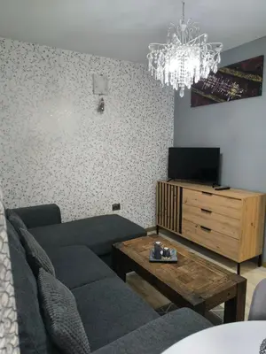 a living room with a couch and a tv and a chandelier at Snowflake- Luxury stay with a Bottle of Wine,free Parking and SPA in Royal Park in Bansko