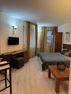 a bedroom with a bed and a desk with a television at Emerald Apartment - complex Bansko in Bansko