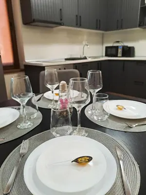 a table with a white plate and wine glasses at Студио Алтом in Pamporovo