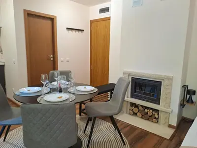a dining room with a table and chairs and a fireplace at Студио Алтом in Pamporovo