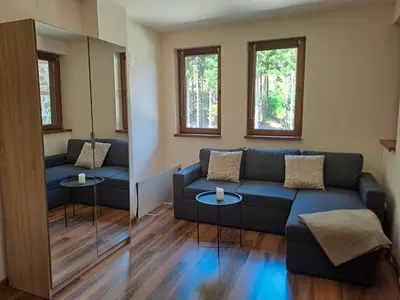a living room with a blue couch and two tables at Студио Алтом in Pamporovo