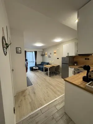 a kitchen and living room with a couch and a table at Pirin Cozy Escape 8 min walk from ski lift - Private Apartment Grand Bansko 1 in Bansko