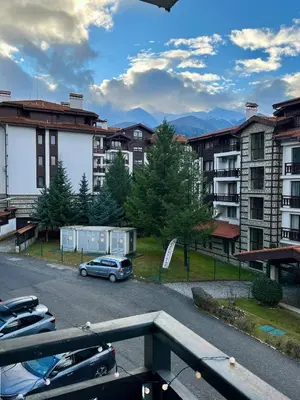 a parking lot with cars parked in front of buildings at Pirin Cozy Escape 8 min walk from ski lift - Private Apartment Grand Bansko 1 in Bansko