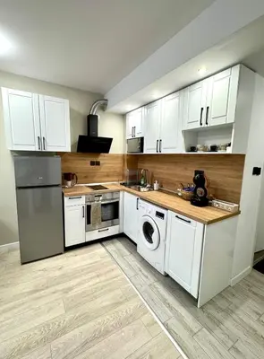 a kitchen with white cabinets and a washer and dryer at Pirin Cozy Escape 8 min walk from ski lift - Private Apartment Grand Bansko 1 in Bansko