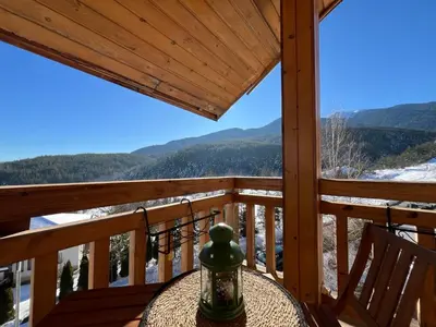 a table on a deck with a view of the mountains at Daliya's Apartment in Bansko
