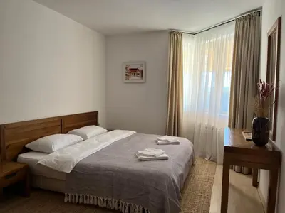 a bedroom with a bed and a table and a window at Daliya's Apartment in Bansko