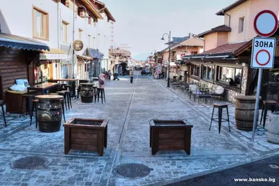 an empty street with tables and chairs and buildings at ELIA Apartment in Bansko