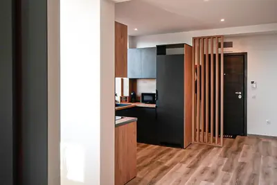 a kitchen with black cabinets and a wooden floor at Апартамент за Гости Танчеви in Karlovo