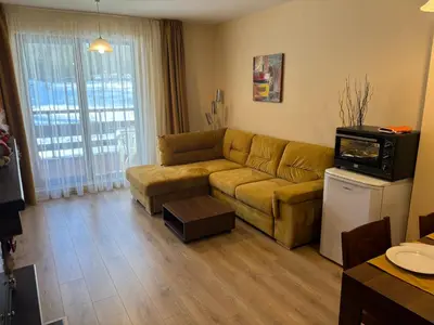 a living room with a couch and a tv at Green life Bansko -view one bedroom apartment in Bansko