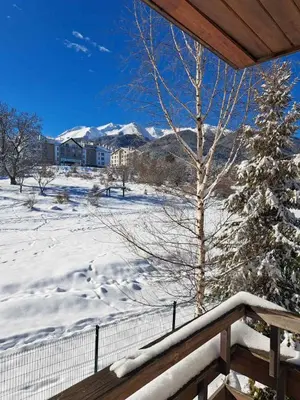 a snow covered porch with a snow covered tree and mountains at Green life Bansko -view one bedroom apartment in Bansko