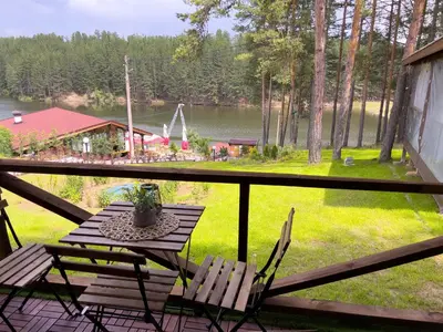 a table and chairs on a balcony with a view of a lake at Къмпинг Alino Lake in Alino