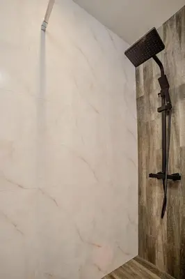 a shower in a bathroom with a stone wall at Holiday home with indoor fireplace in Pamporovo