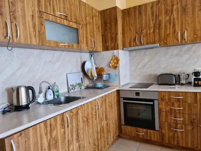 a kitchen with wooden cabinets and a sink at Zweizimmerwohnung mit Bergblick in Bansko